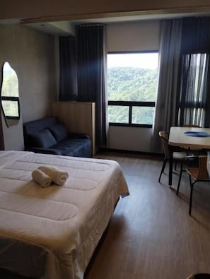 Een hotelkamer met een bed, een tafeltje, een stoel en uitzicht op de omgeving.