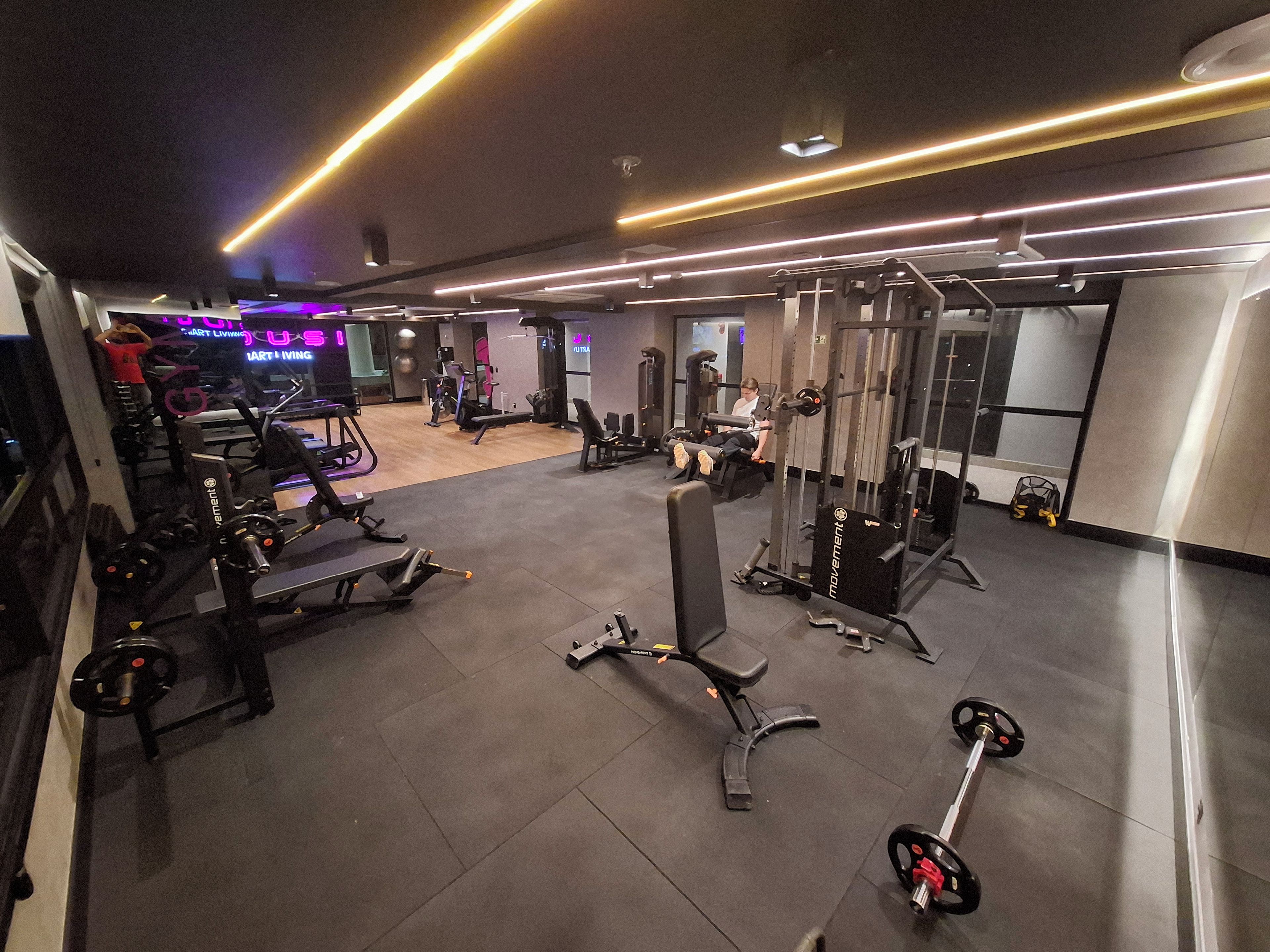 Un gimnasio con varios equipos de ejercicio, que incluyen máquinas de pesas y pesas libres.