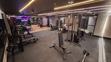Un gimnasio con varios equipos de ejercicio, que incluyen máquinas de pesas y pesas libres.