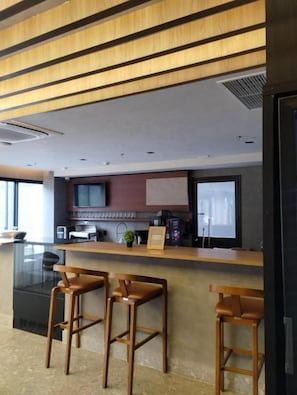 Een moderne keuken met een houten aanrecht, barstoelen en een televisie.