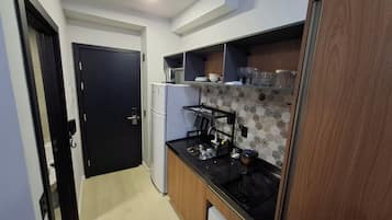 Cocina compacta con refrigerador, estufa y microondas. Hay una puerta que da a otra habitación.