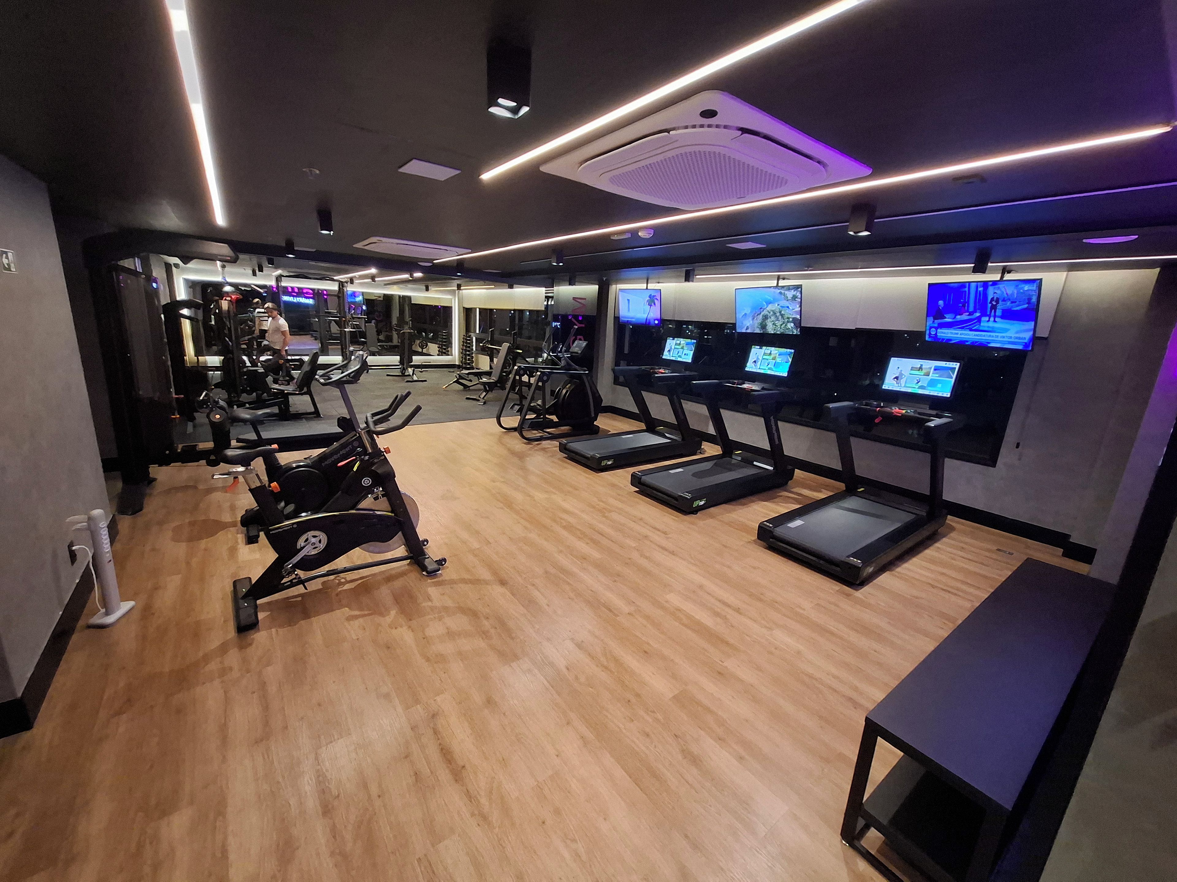 Un gimnasio con cintas de correr, máquinas de pesas y colchonetas de ejercicio.