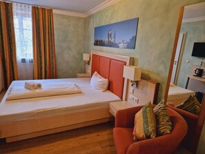 Een hotelkamer met een bed, een rode bank, een schilderij van een kathedraal en een televisie aan de muur.