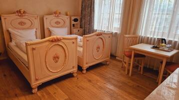 Ein Zimmer mit zwei Betten, einem kleinen Tisch und einem Stuhl.