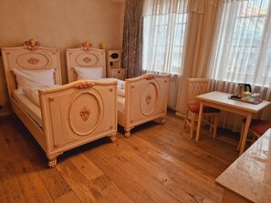 Een kamer met twee bedden, een tafeltje en een stoel.
