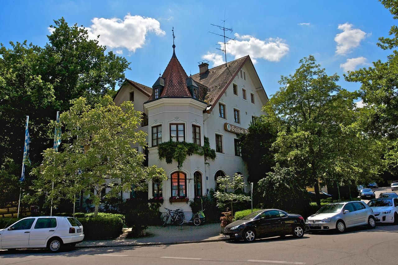 Ein historisches Gebäude mit einem Turm, parkenden Autos und Fahrrädern.
