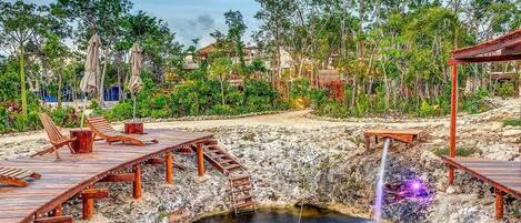 A natural hot spring with wooden walkways and lounge chairs.