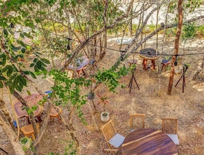 An outdoor seating area with tables and chairs, surrounded by trees and plants. - Jungle Retreat with 2 Pools & Cenotes in vibrant Tulum (Tulum)