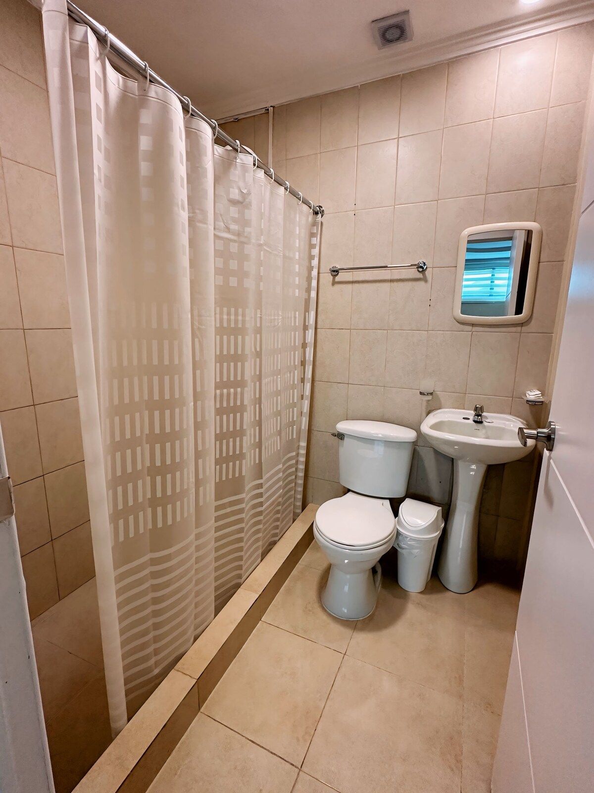 A bathroom with a shower curtain, a toilet, a bidet, and a sink.