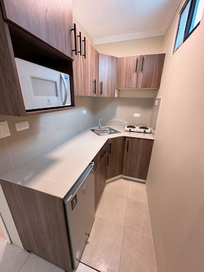 A compact kitchen with a built-in microwave, a sink, and a stove.