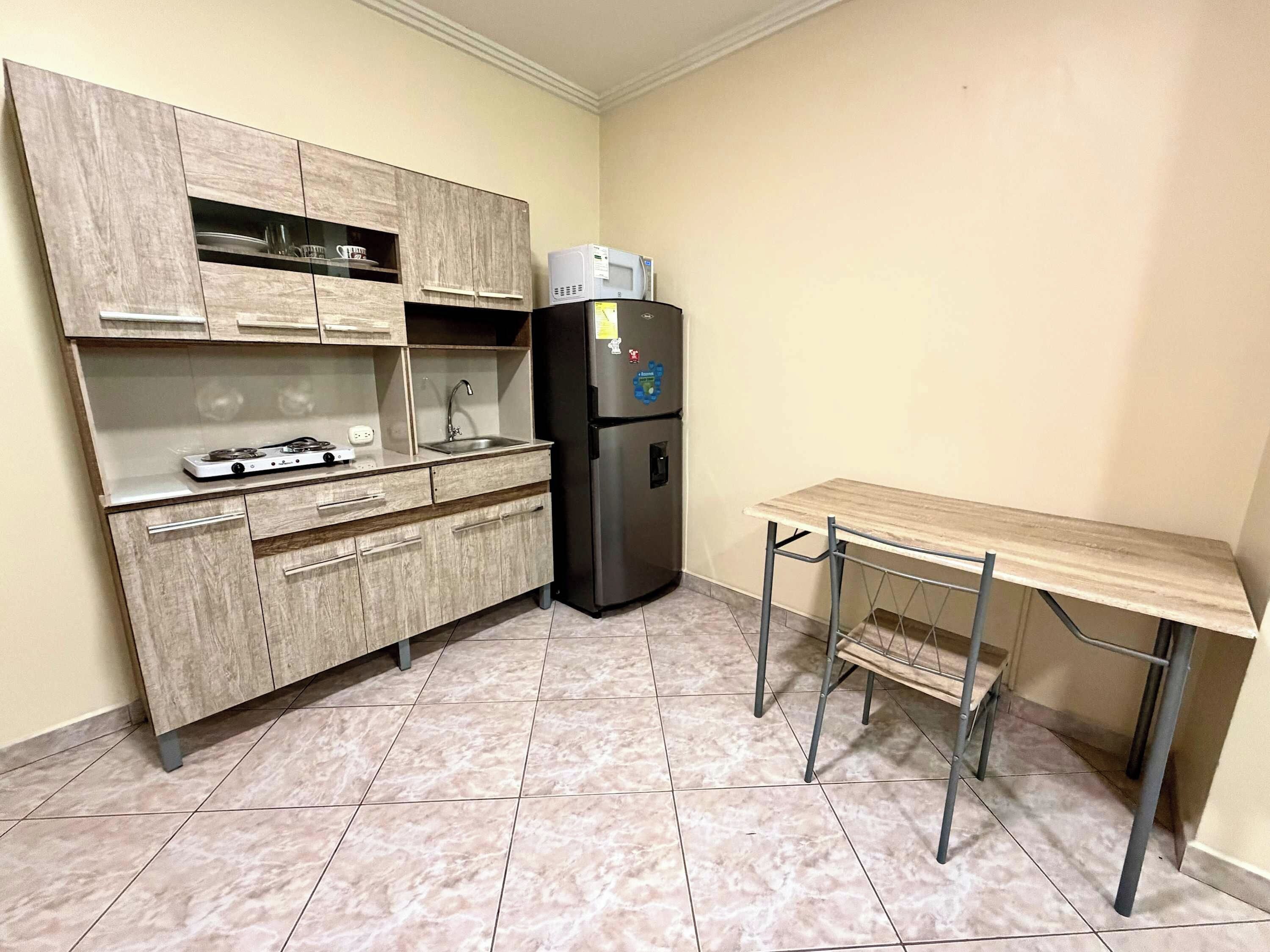 A compact kitchen with a built-in stove, a sink, and a refrigerator.
