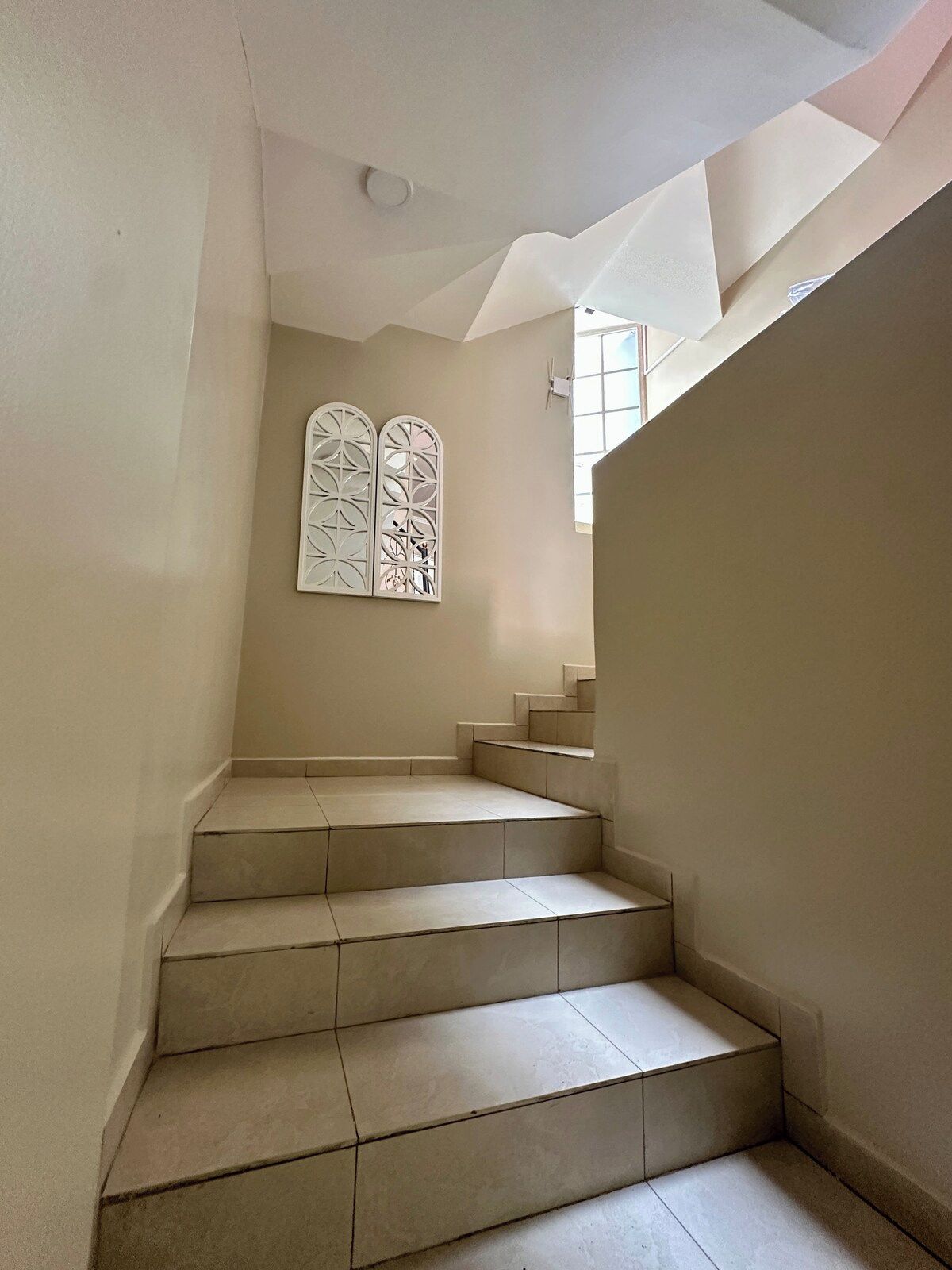 Un escalier doté d’un plafond au motif géométrique et d’un panneau décoratif fixé au mur.
