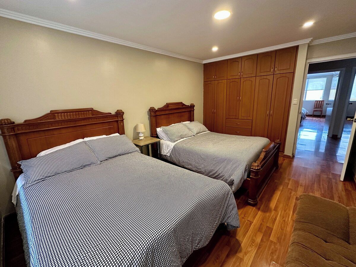 Ein Schlafzimmer mit zwei Betten, Holzkopfteilen, einem Nachttisch und einem Kleiderschrank.