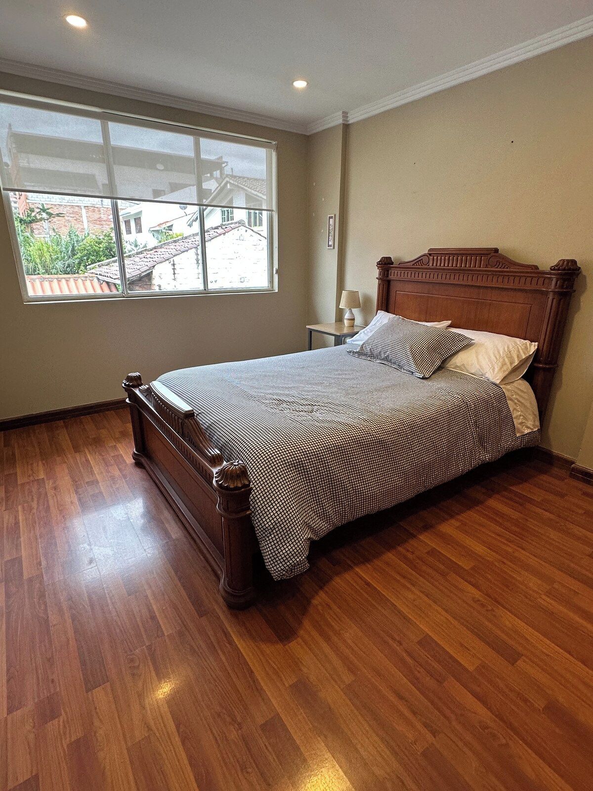Un dormitorio con cama de madera, ventana y mesita de noche.