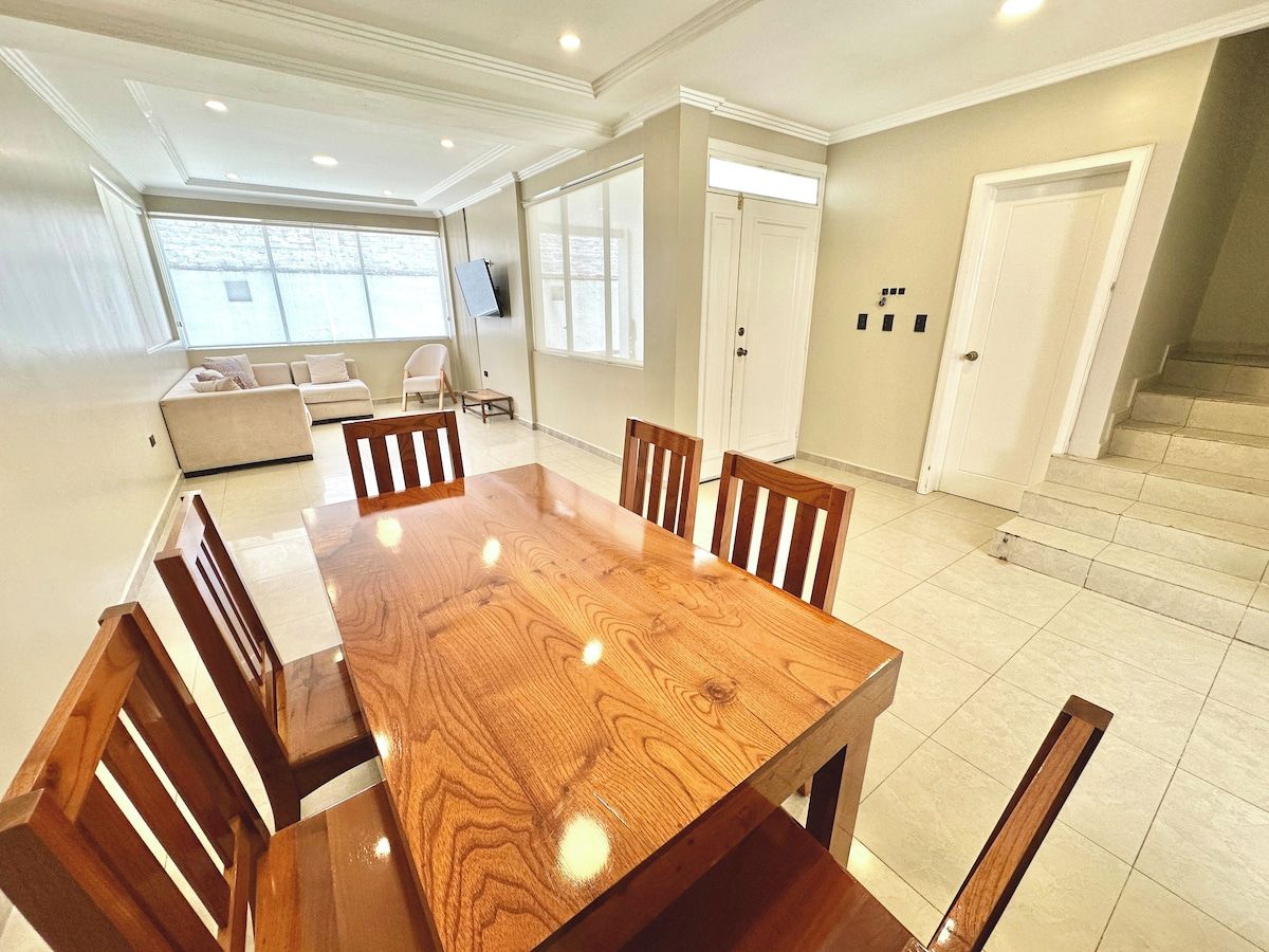 Un comedor con una mesa y sillas de madera, un sofá y un televisor.