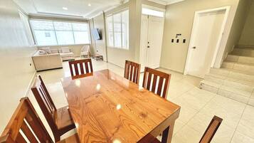 Un comedor con una mesa y sillas de madera, un sofá y un televisor.