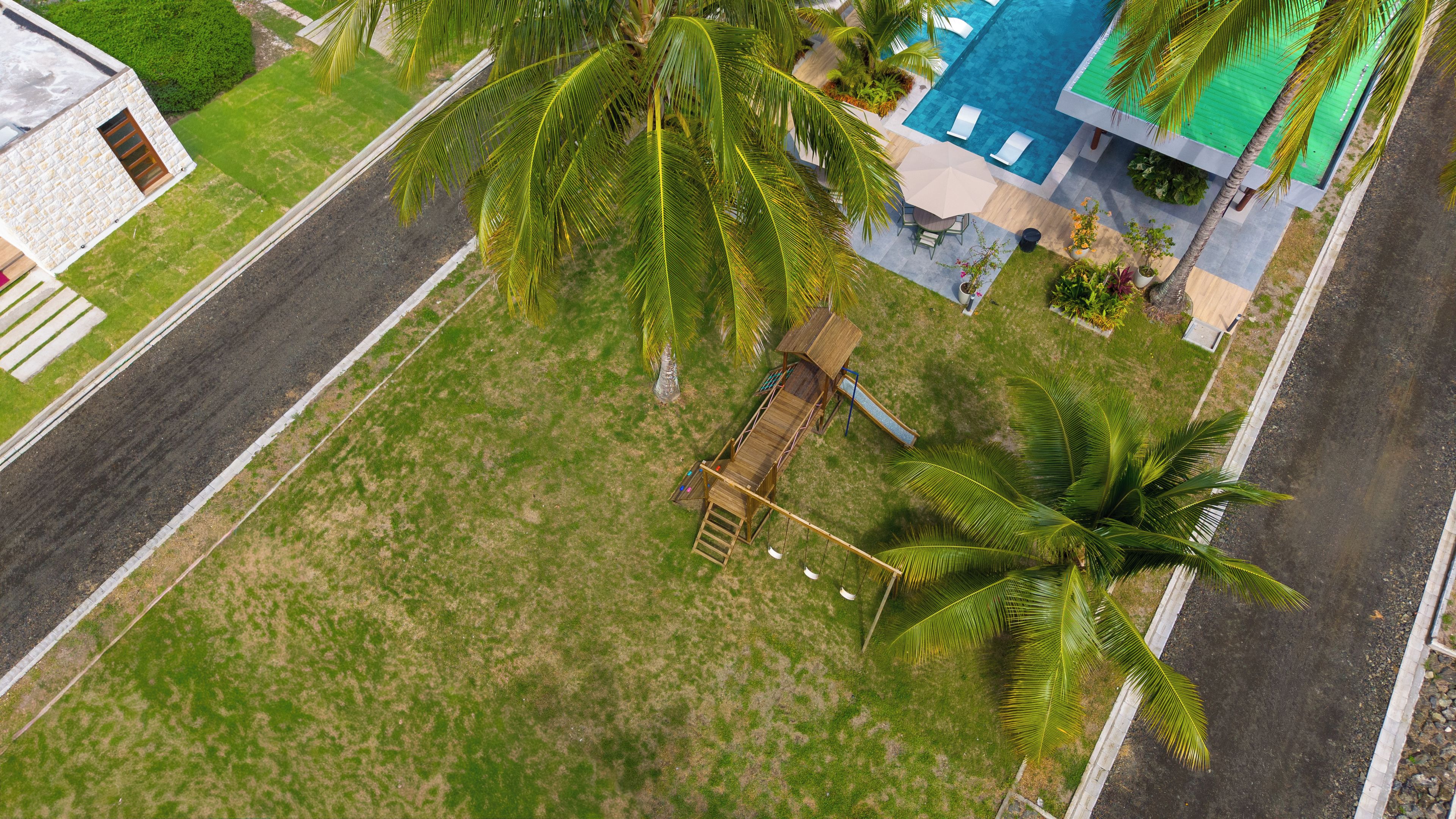 An aerial view of a property with a swimming pool, palm trees, and a wooden deck.