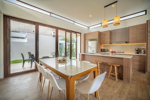 Une cuisine moderne dotée d’un îlot central, de meubles en bois et d’un coin repas avec une table et des chaises en verre.