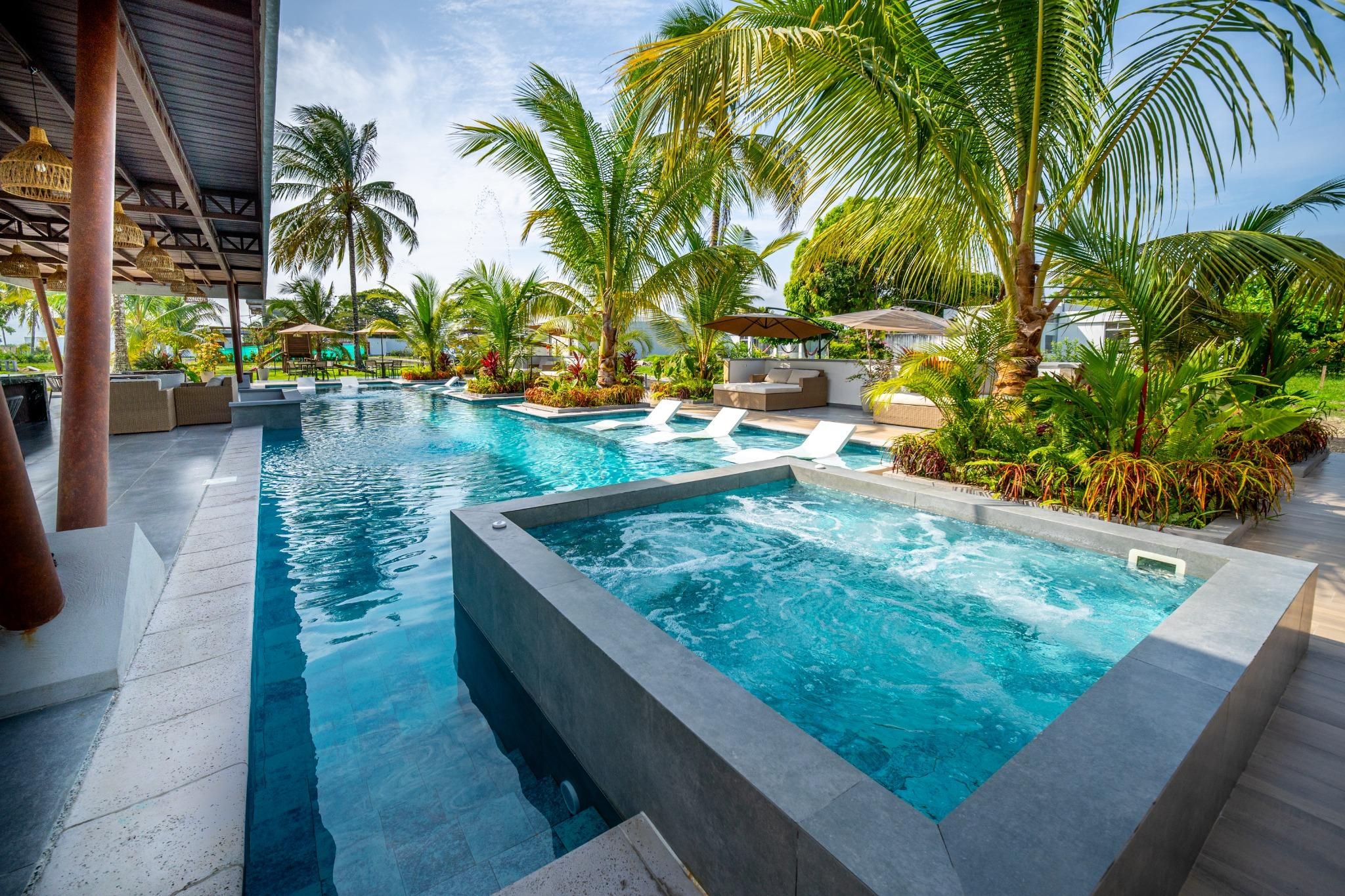 A swimming pool with multiple lanes, surrounded by palm trees and lounge areas.