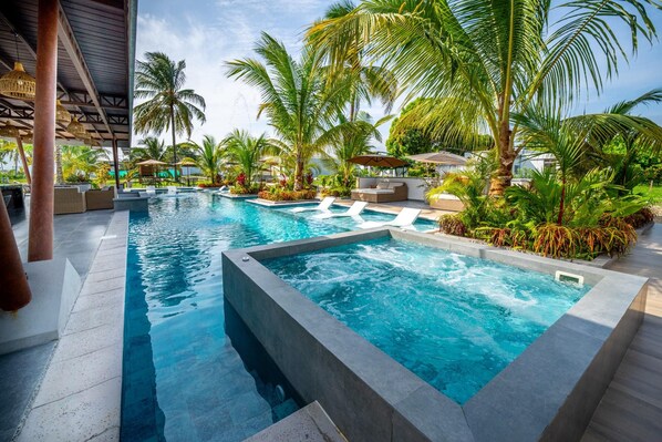A swimming pool with multiple lanes, surrounded by palm trees and lounge areas.