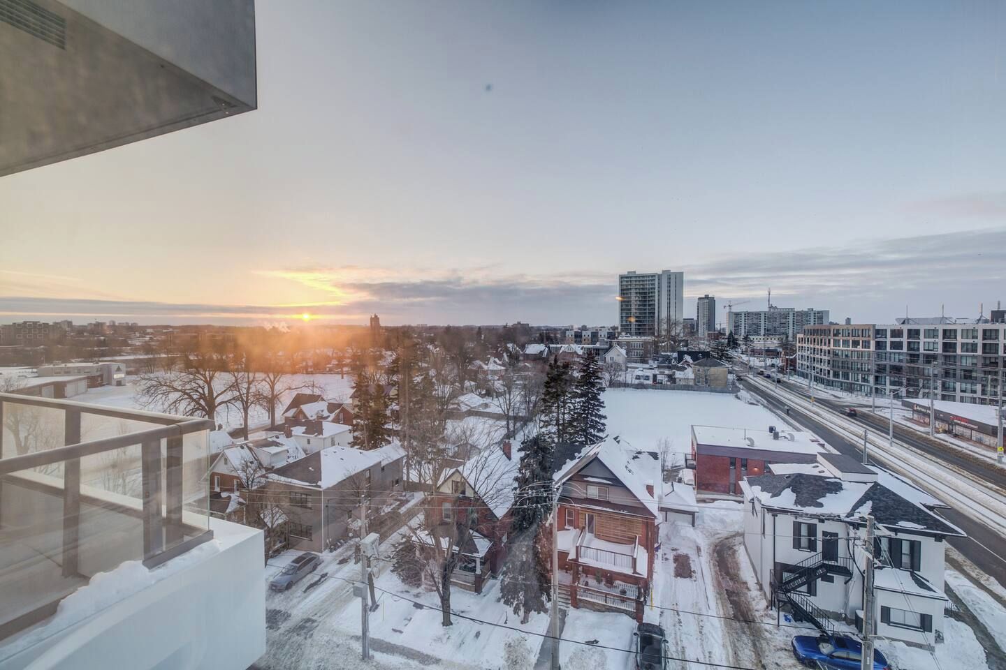 Une vue d’une ville au coucher du soleil, avec des bâtiments et un sol recouvert de neige.