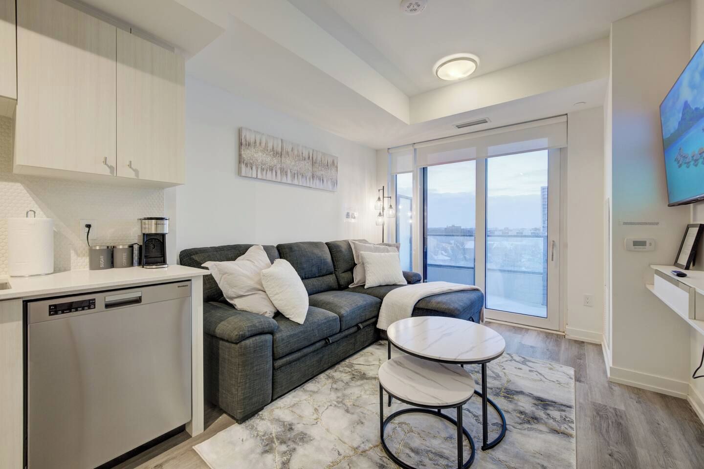 A modern living room with a sofa, a coffee machine, and a dining area with a table.