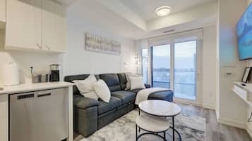 A modern living room with a sofa, a coffee machine, and a dining area with a table.
