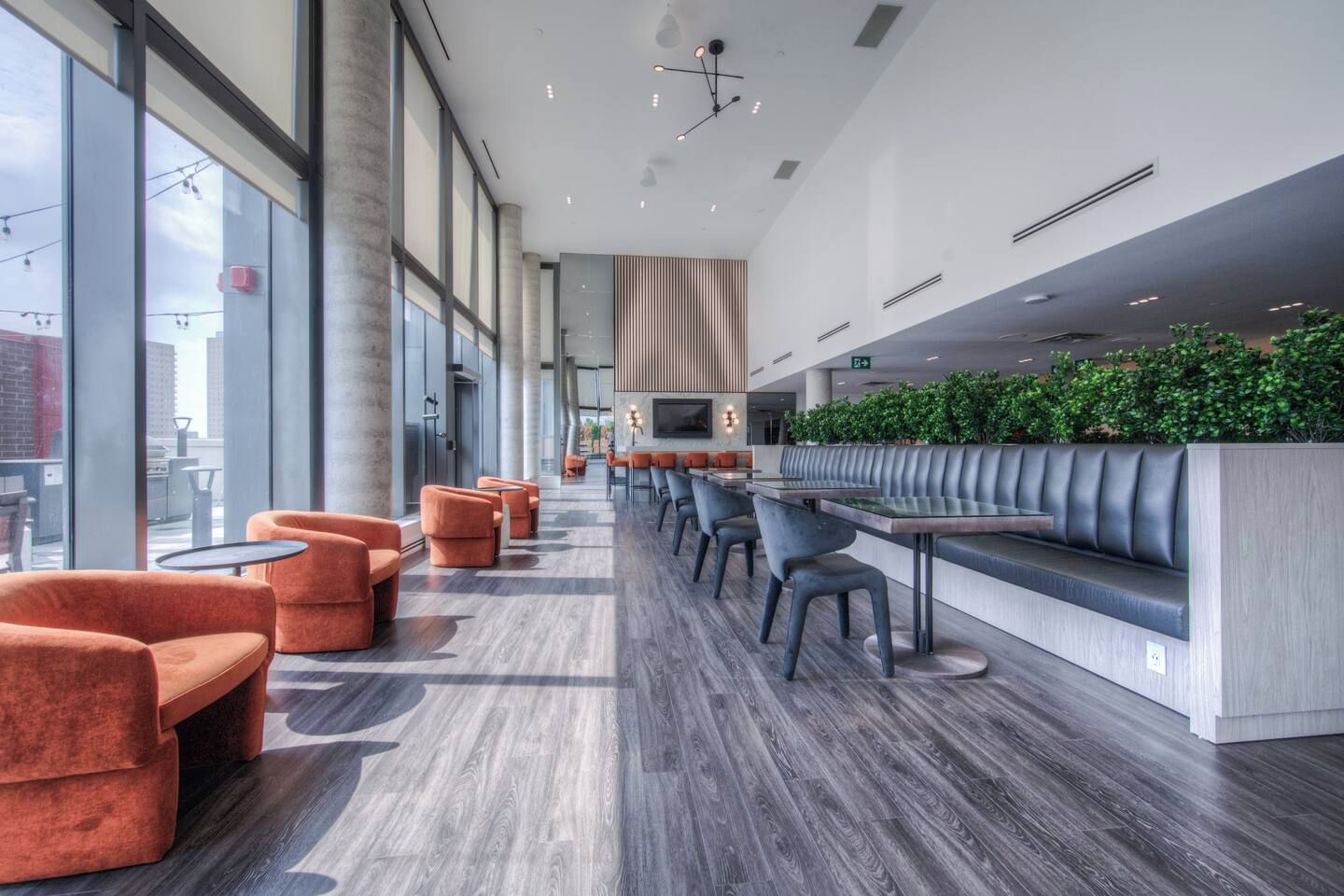 A modern indoor space with a long bench seating area, tables, and chairs.