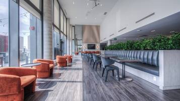 A modern indoor space with a long bench seating area, tables, and chairs.