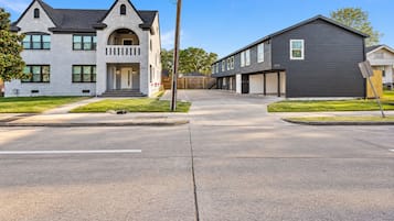 A residential street with two houses, one with a grey facade and the other with a dark grey facade.