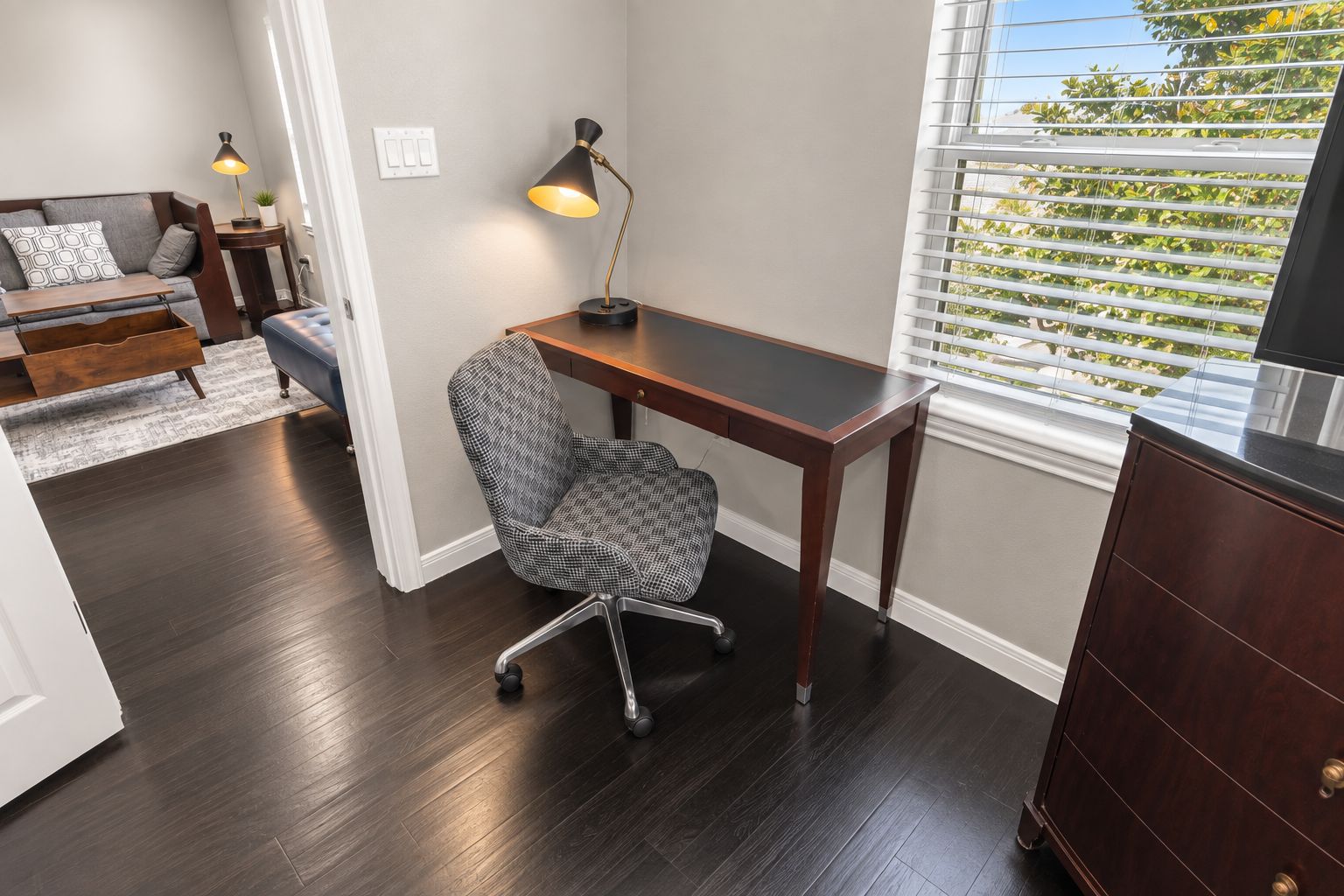 A modern office space with a desk, chair, and a window with blinds.
