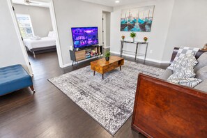 Una sala de estar moderna con una televisión de pantalla plana, una mesa de centro, un sofá y una alfombra estampada.