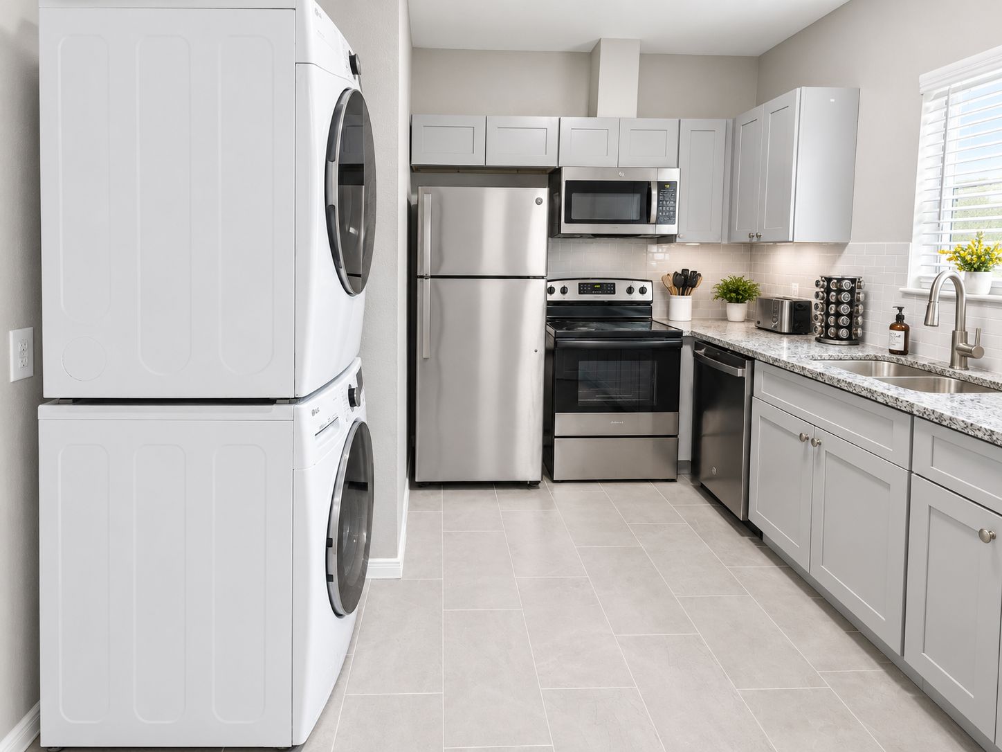 Una cocina moderna con electrodomésticos de acero inoxidable, incluyendo lavadora, refrigerador, microondas, horno y lavavajillas.