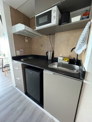 Cocina compacta equipada con microondas, hervidor y lavabo.