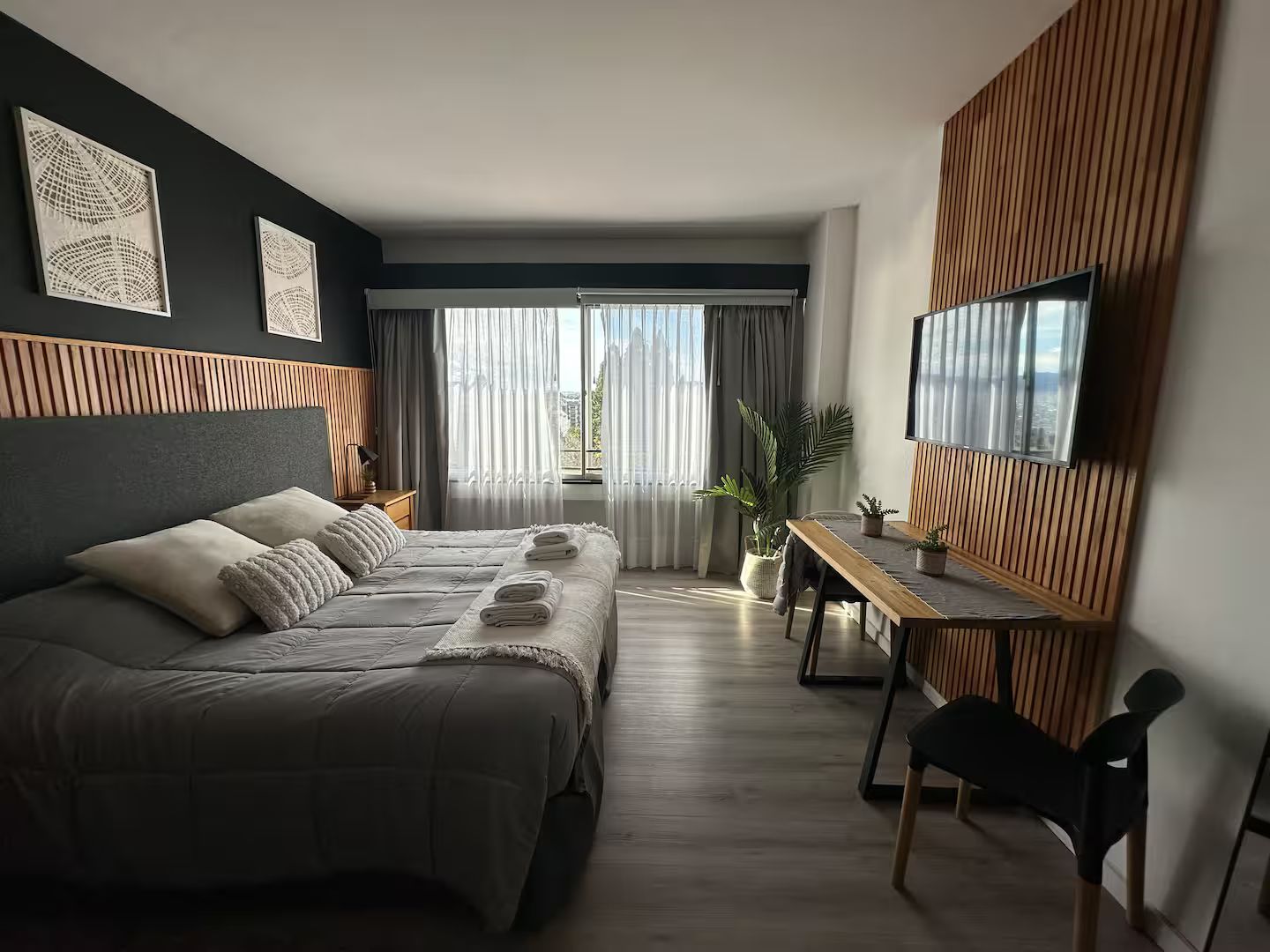 Une chambre d’hôtel moderne avec un grand lit, un bureau et une télévision.
