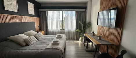 Une chambre d’hôtel moderne avec un grand lit, un bureau et une télévision.