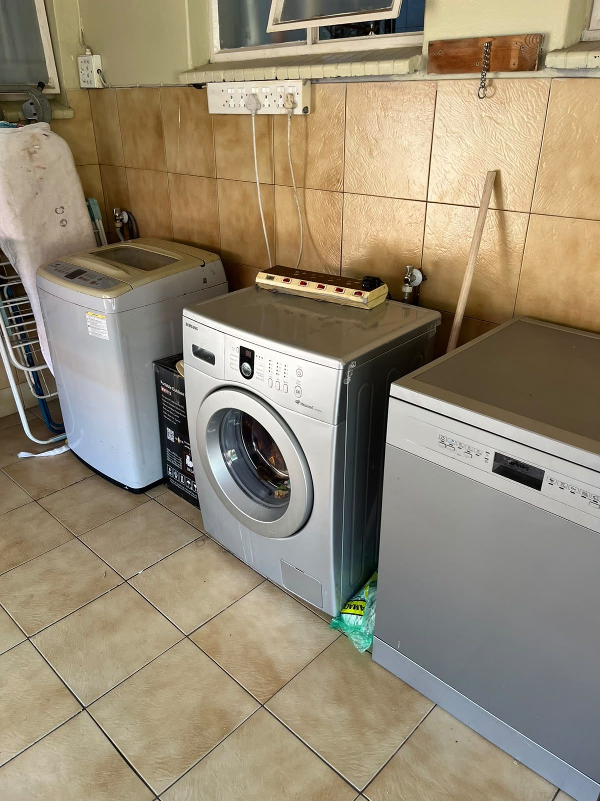 A laundry room with a front-loading washing machine, a dryer, and a utility shelf above the washing machine.