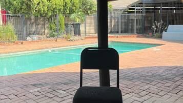 A covered outdoor area with a pool, a chair, and a table.