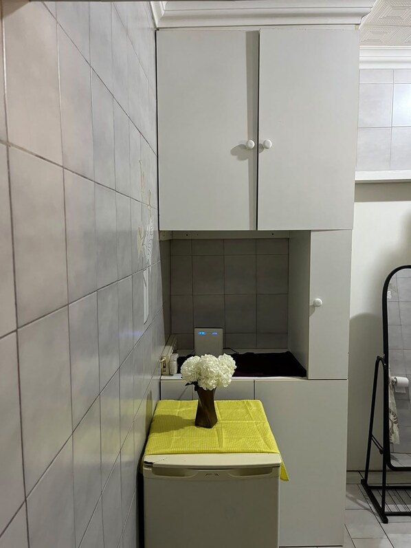 A kitchen with a white cabinet, a yellow mat on the counter, and a white flower vase.