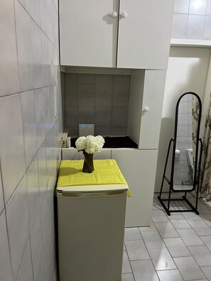 Une salle de bain avec un meuble blanc, une petite fenêtre et des toilettes.
