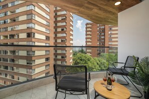 Ein Balkon mit zwei Stühlen, einem kleinen Tisch und einer Weinflasche.