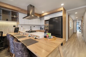 Eine moderne Küche mit einer zentralen Kochinsel, Edelstahlgeräten und einem Essbereich aus Holz.