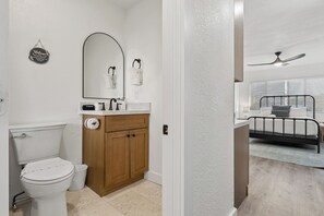 A bathroom with a toilet, vanity, and a mirror. - Cozy Studio Retreat | Quiet | Kitchenette (Phoenix)