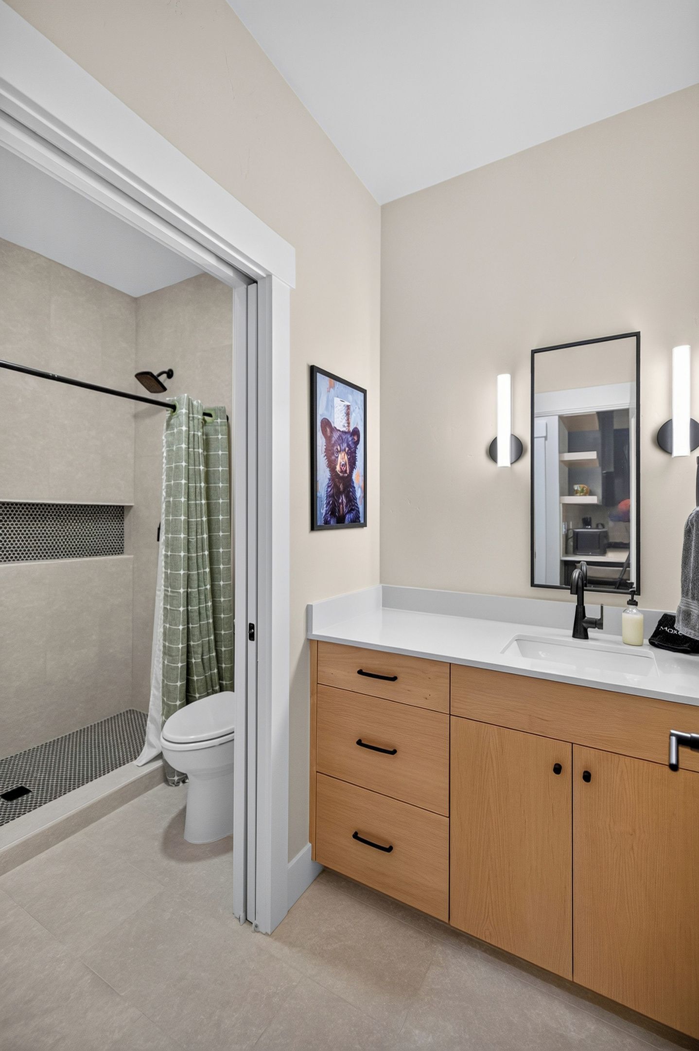 A modern bathroom with a shower, toilet, vanity, and a framed picture on the wall.