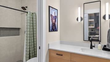 A modern bathroom with a shower, toilet, vanity, and a framed picture on the wall.
