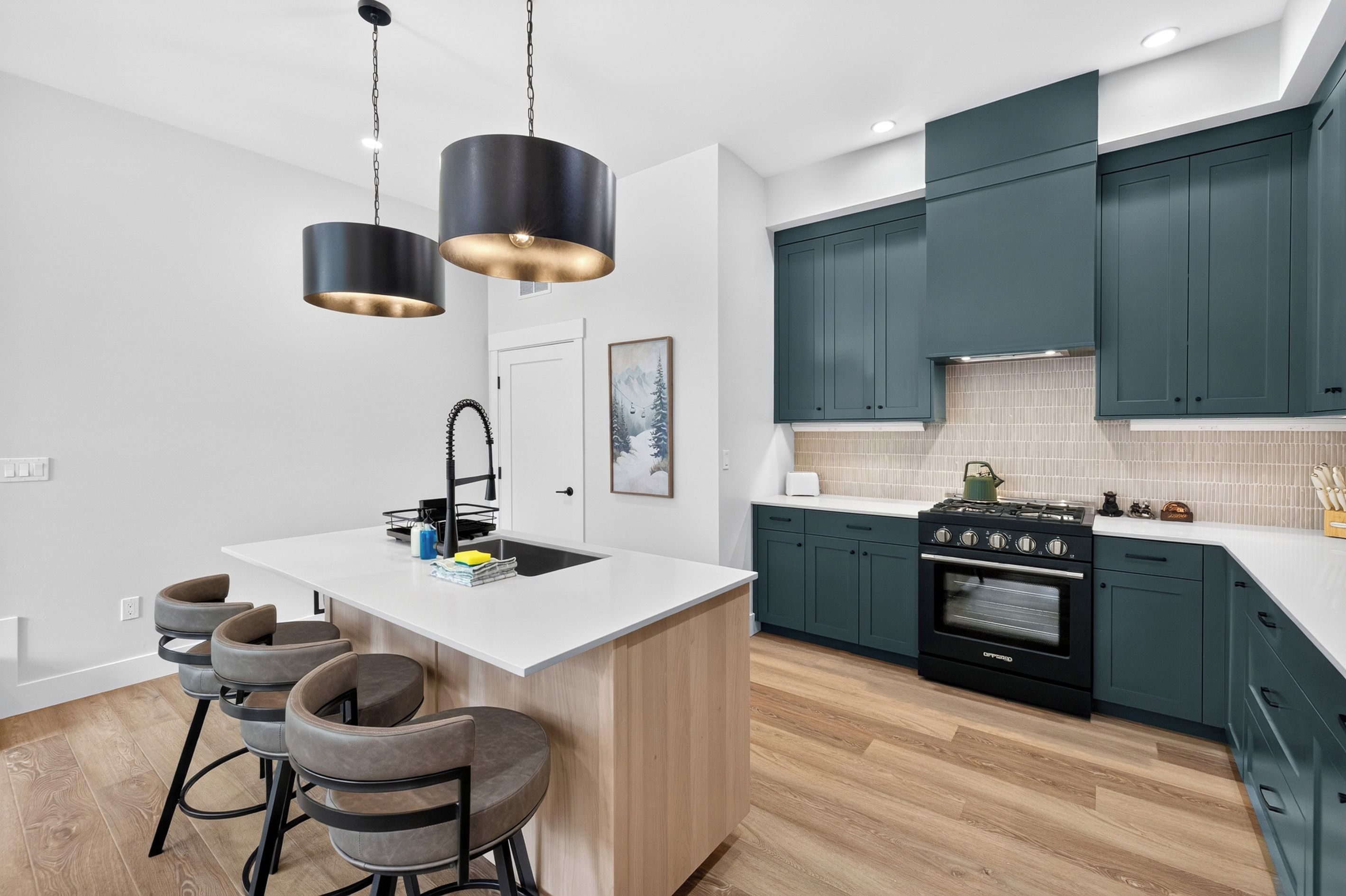 Una cocina moderna con una isla central, taburetes de bar, estufa y pileta.