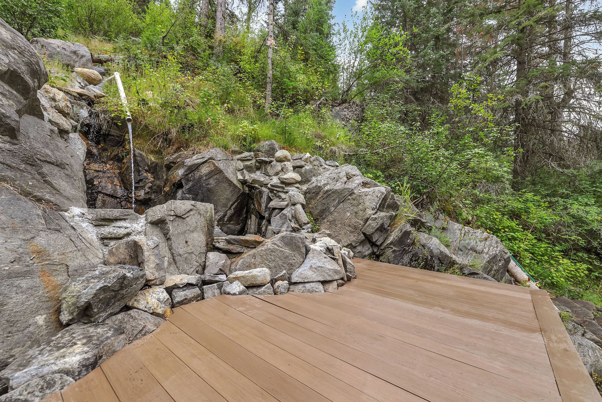Una terraza de madera con un paisaje rocoso y un bosque denso al fondo.