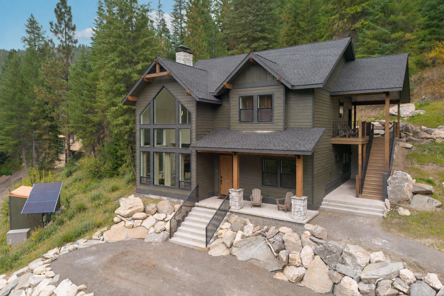 A modern house with a stone foundation, large windows, and a covered porch.