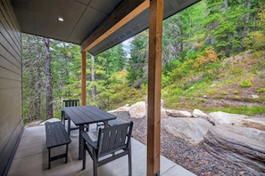 Un patio al aire libre con una mesa y sillas, rodeado de un paisaje natural con árboles y rocas.