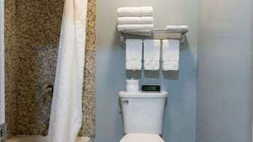 A bathroom with a shower, toilet, and a towel rack.